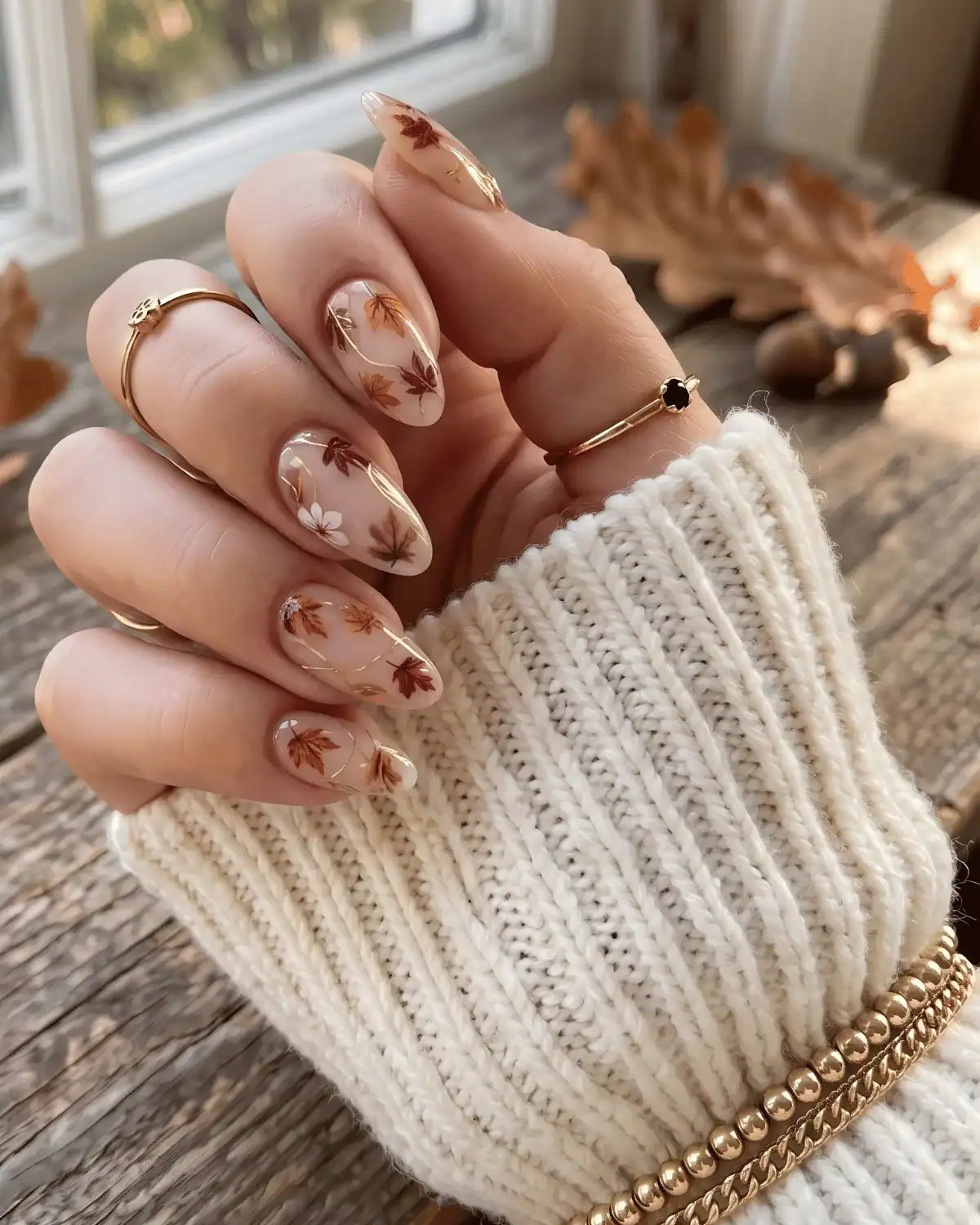 Sheer nude nails with amber and rust leaf details and gold accents