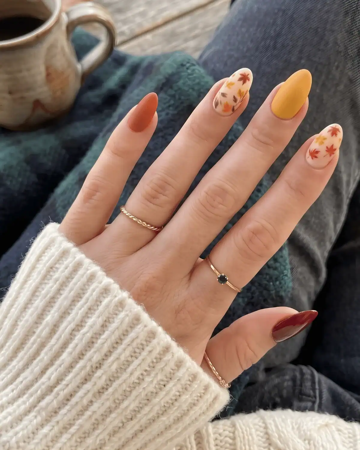 Burgundy and nude nails with cascading orange and red leaf art