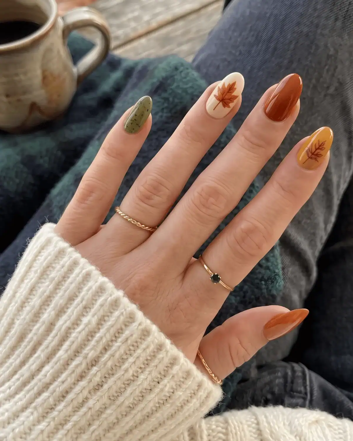 Terracotta, olive, beige, and mustard nails with hand-painted leaf details