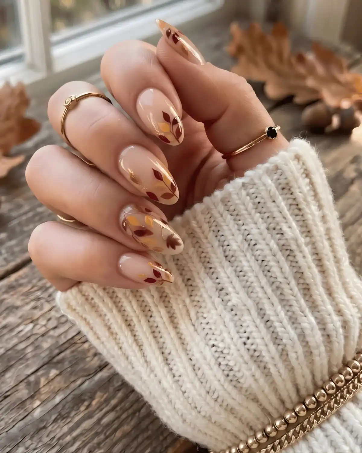 Nude nails with cascading mini leaf art in mustard, orange, and gold