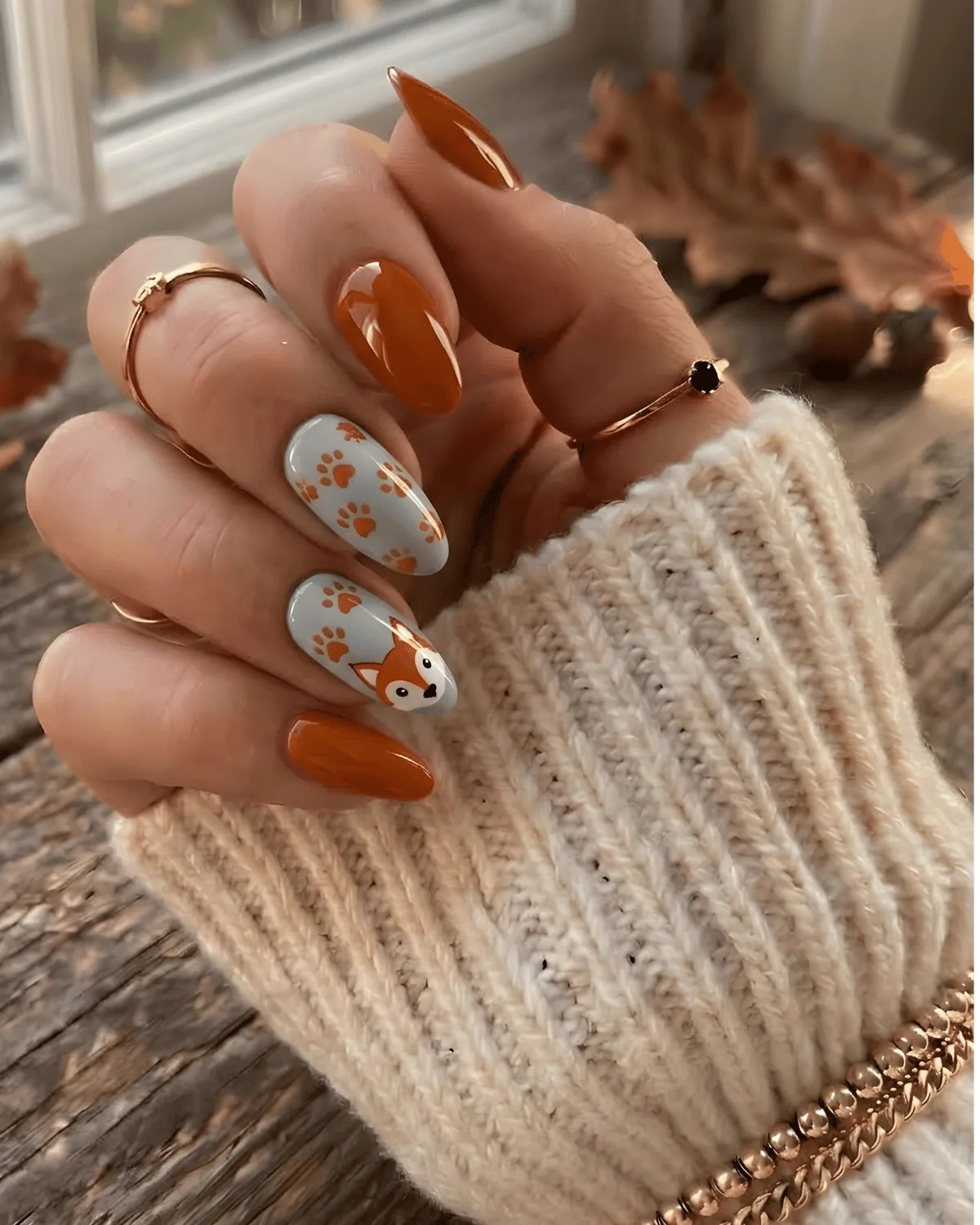 Orange nails with cartoon fox face and paw print nail art