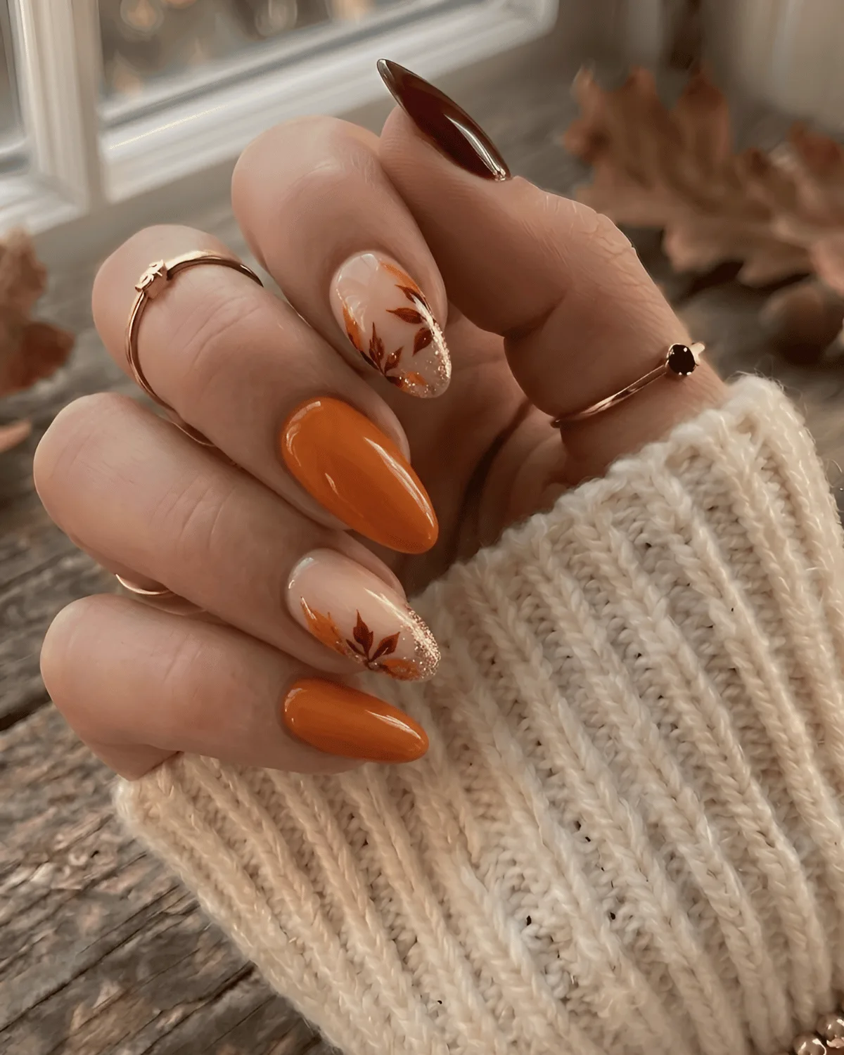 Burnt orange and burgundy nails with gilded leaf nail art