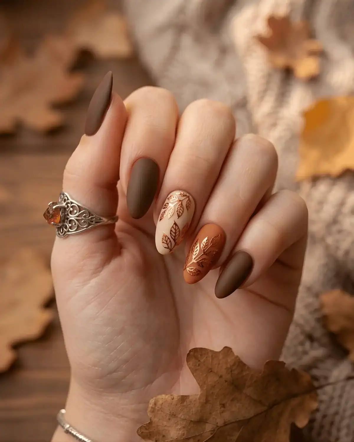 Matte chocolate brown nails with metallic copper leaf cutout accents