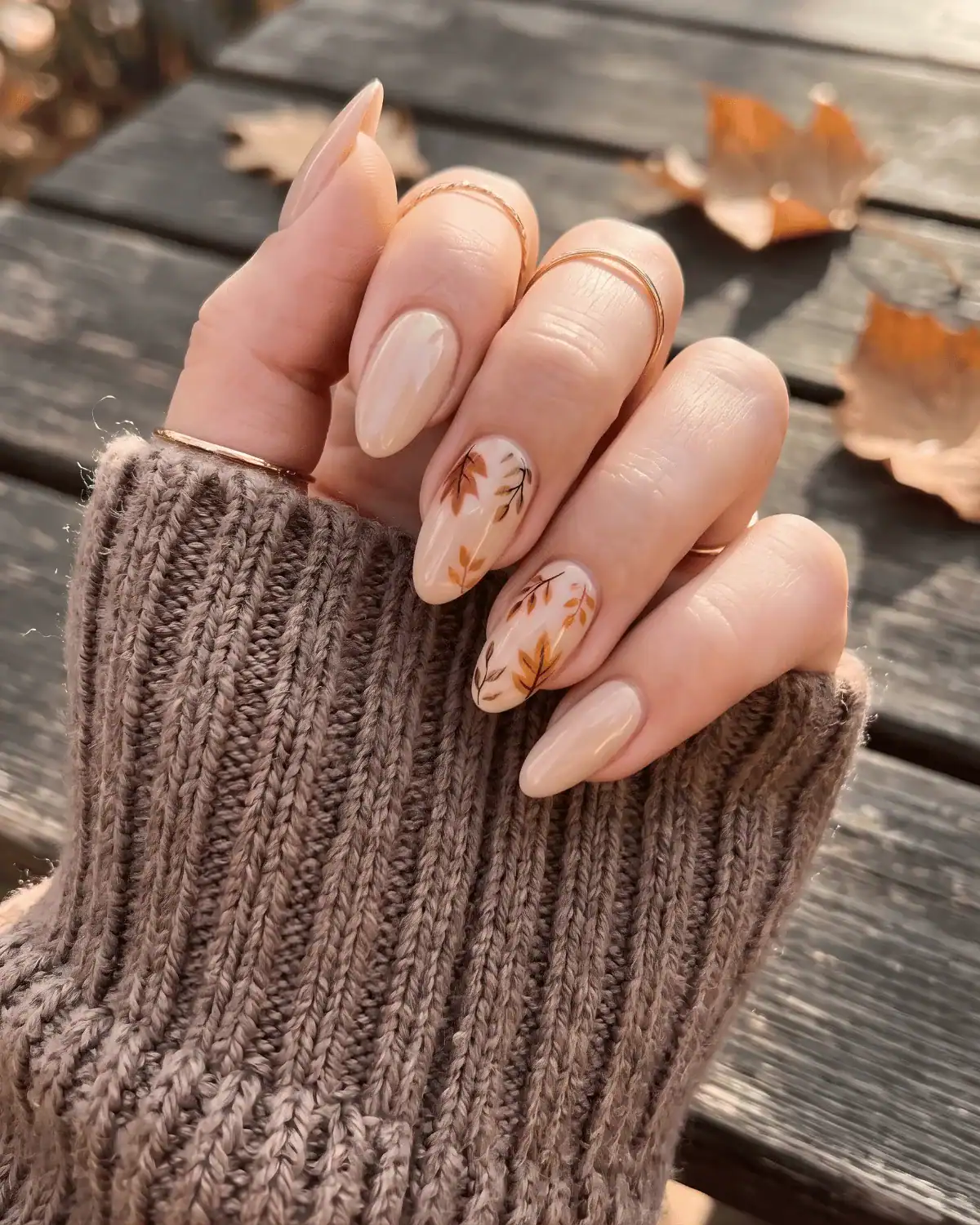 Beige glossy nails with delicate rust and burnt orange leaf art