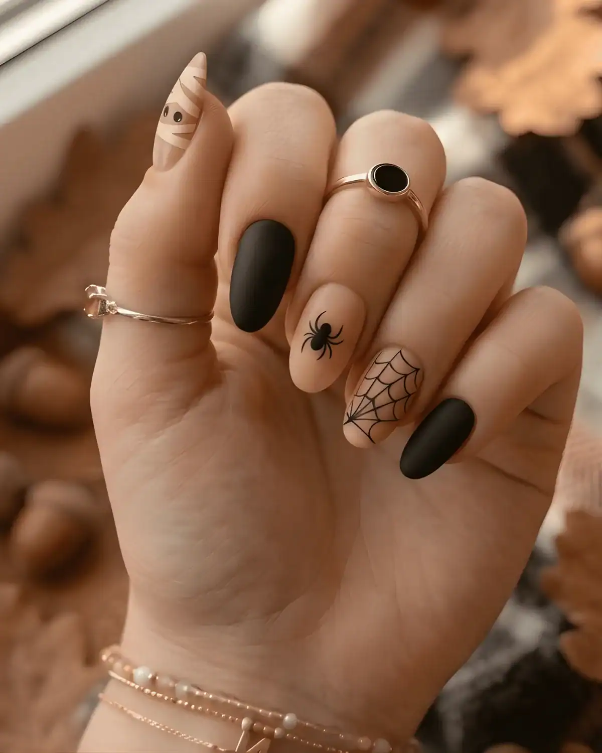 Halloween nail art with black spiderwebs, spider, and mummy-wrapped accent nail